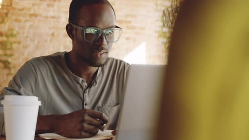 Afro-American Businessman Video Calling on Laptop in Cafe