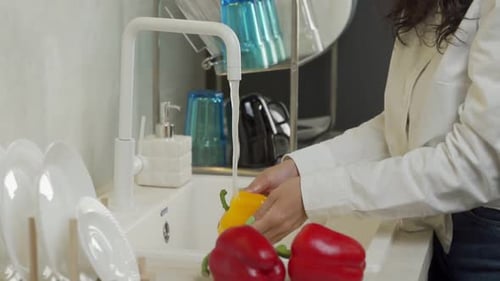 Woman Washing Yellow Pepper in Kitchen Sink