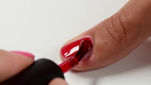 Master Covers the Nail of Client By Red Varnish. Close Up