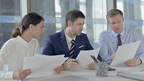 Middle Aged Businessman Having Talk on Documents with His Assistants on Office Table