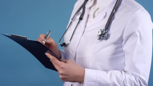 Medical Professional Writing on Clipboard in Close Up