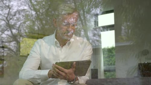 Älterer Mann benutzt Tablette zu Hause