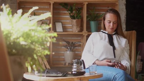 Eine Frau benutzt ein Smartphone in einem Café.