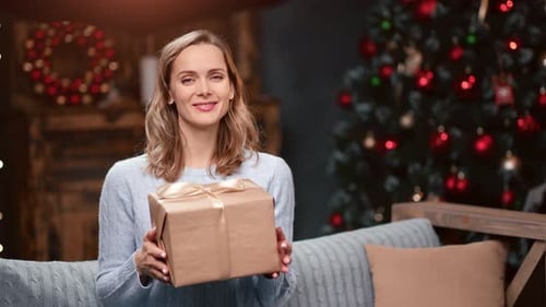 Smiling Woman Holding Christmas Present at Home