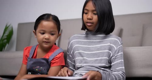 Handheld shot of The older sister teach the younger sister to read book