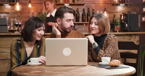Three Friends Looking at Laptop in Cafe