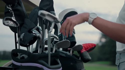 Woman Selects Golf Clubs on Green Golf Course