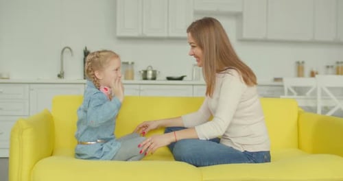 Woman and Girl Chat on a Yellow Couch
