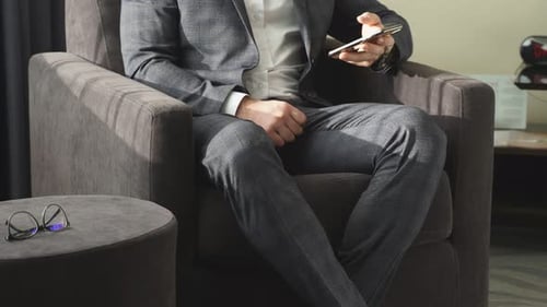 Man in Suit Sitting in Chair With Smartphone