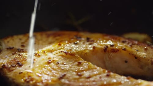 Pouring Lemon Juice on Salmon Steak