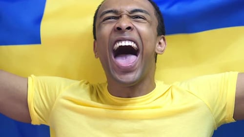 Man Yelling and Cheering in Front of Swedish Flag