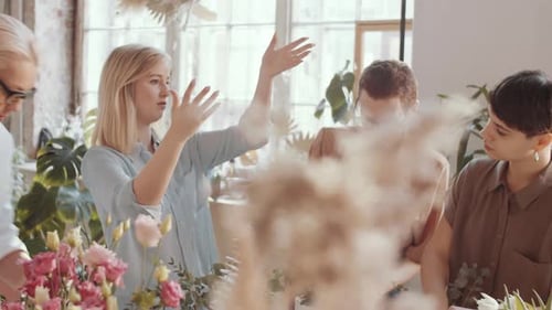 Experienced Female Florist Explaining How to Make Bouquet to Colleagues