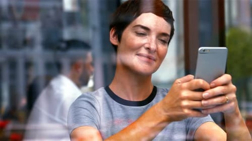 Woman Uses Smartphone in Cafe Drinking Coffee