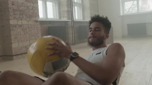 Afro-Sportler macht Side Crunches mit Gewichtsball