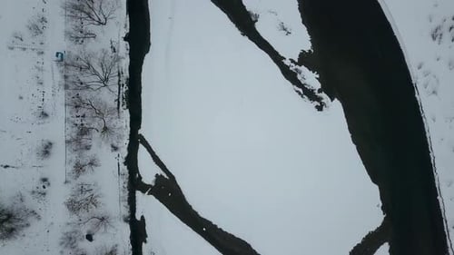 Aerial Down View of a Riwer in Winter with Snow Covered White Banks