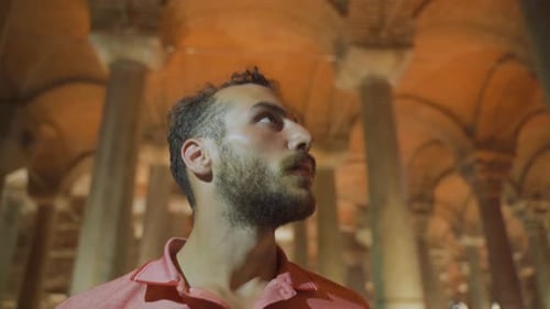 Man Looks Up at Ancient Columns at Night