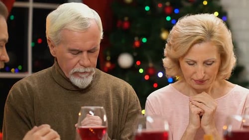 Família extensa orando antes da refeição de Natal, bênção do jantar, espírito natalino