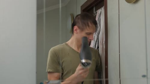 Man Styling Hair with Dryer and Comb in Bathroom