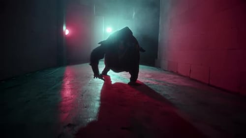 Hooded Dancer Performing Urban Dance in a Dark Club