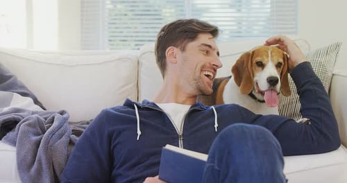Young Man Relaxing with Beagle Petting the Dog