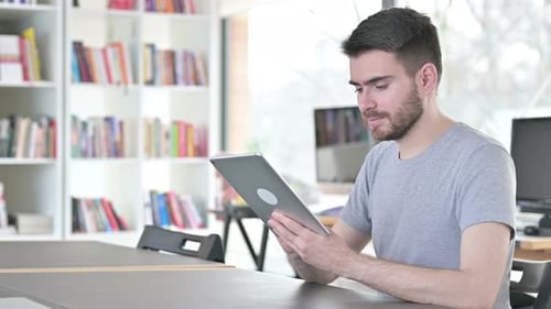 Serious Young Man Using Digital Tablet in Office