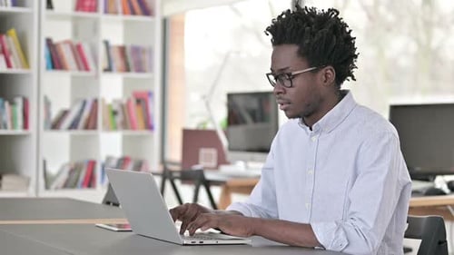 Young Man Working on Laptop in Modern Office