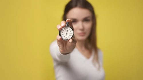 Woman Holding Stopwatch Shows Time Passing in Studio