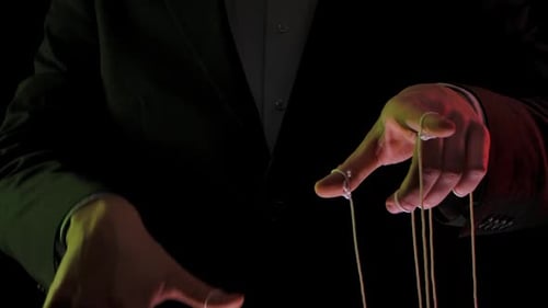Geschäftsmann Leader in einem Anzug manipuliert die Marionettenschnüre, die an seine Finger gebunden sind