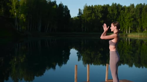 Young Woman Practicing Yoga on the Wooden Berth at Lake. Single Sport Healthy Training on Nature at