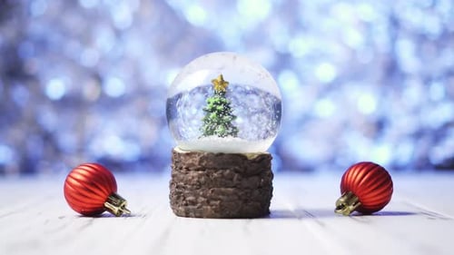 Close-up of Snowflakes Swirling Around a Christmas Tree Inside a Glass Ball