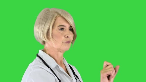 Mature Woman Doctor Pointing Against Green Screen