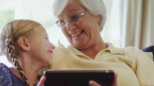 Smiling Girl and Senior Woman Viewing Tablet Device