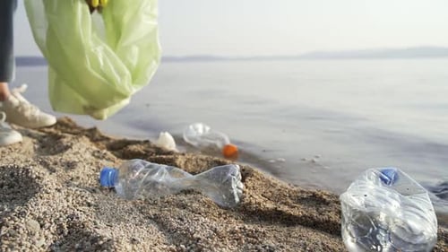 Un voluntario coloca botellas de plástico vacías, servilletas sucias y papeles usados en una bolsa de basura