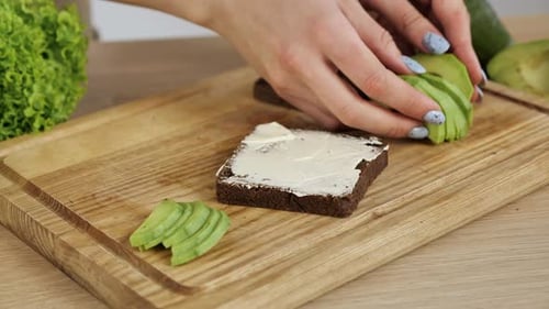 Preparing avocado toast on wooden cutting board