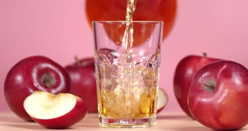 Pouring Apple Juice into a Glass with Apples