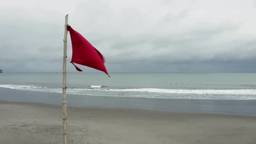 Red Flag Waving on Beach on Overcast Day