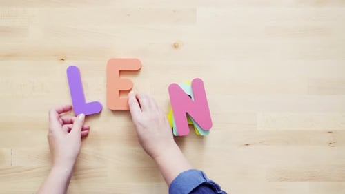 Hands Spell "Learn" With Bright Letters on Wood