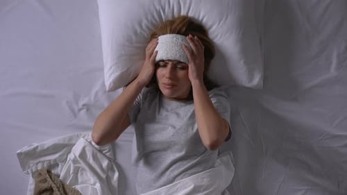 Woman Lying in Bed with a Towel on Her Forehead