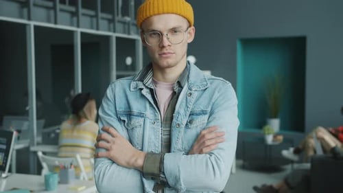 Zeitlupenporträt eines selbstbewussten jungen Hipsters, der lächelnd im modernen Coworking Center steht