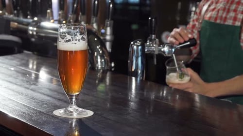 Glass of Beer on Bar with Bartender Pulling Tap