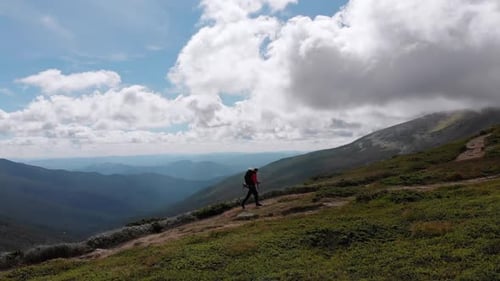Aerial View of a Traveler Photographer with Backpack Climbing By Mountain Range