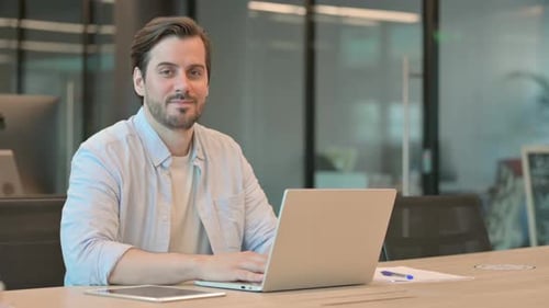 Man Working on Laptop Smiles in Office