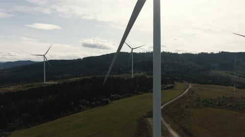 Aerial Drone Shot of Wind Turbines in the Forest Near the Sea at Sunset. Shot in (UHD).