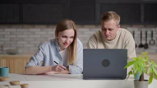 Couple Reviews Finances Together at Home Using Laptop