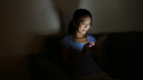 Woman Using Phone in Dark Home at Night