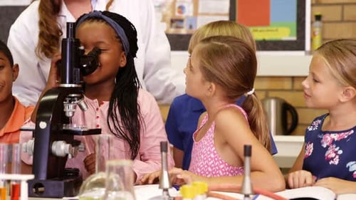 Teacher assisting school kids with experiment in laboratory
