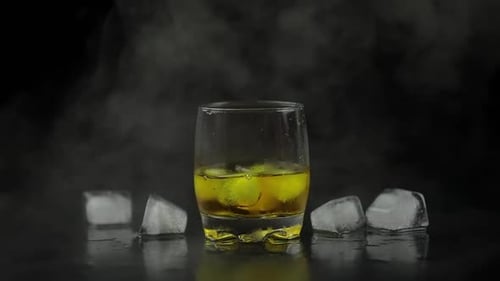 Whiskey with Ice. Pouring Whisky Rum From the Bottle on Black Background