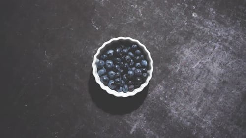 Myrtilles biologiques fraîches dans un mini-bol sur une table noire vintage