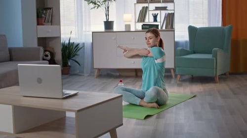 Adorable Girl in Sportswear Doing Physical Exercises Using Video Lessons on Laptop in Living Room at