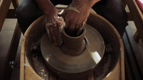 Mains d'un jeune potier travaillant sur un tour de potier et fabriquant un pot